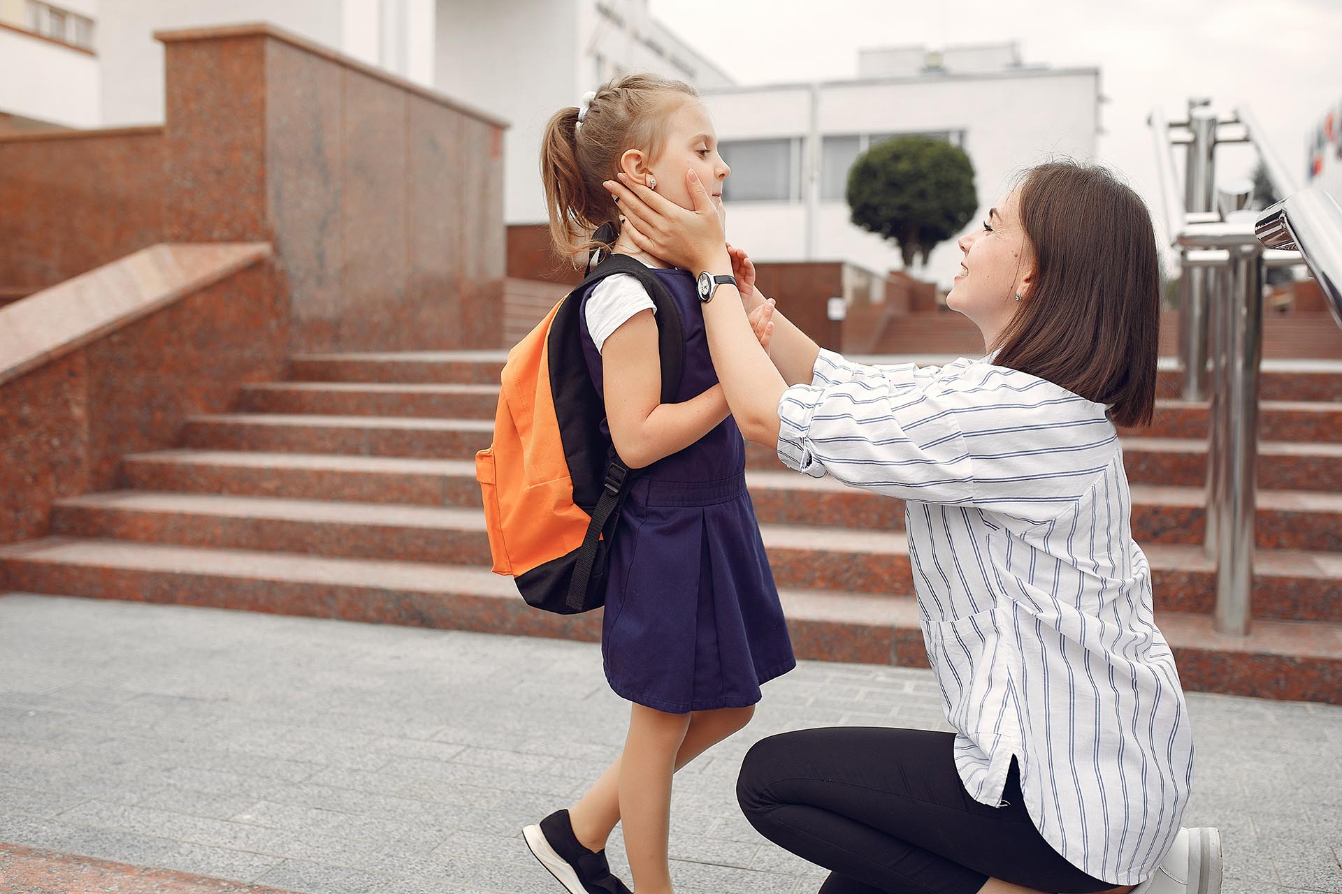 mother kneeling down adjusting kids clothes